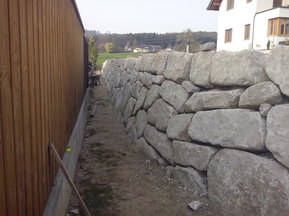 unbearbeitete Steinmauer neben Gebäude