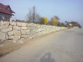 unbearbeitete Steinmauer neben Straße